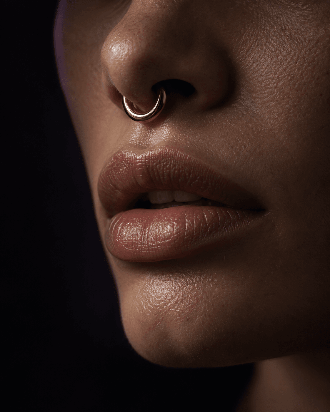 Piercing de septo em ouro visto em close com boca entreaberta.