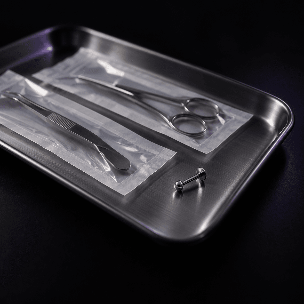 Detalhe de instrumentos esterilizados e uma joia sobre campo escuro.